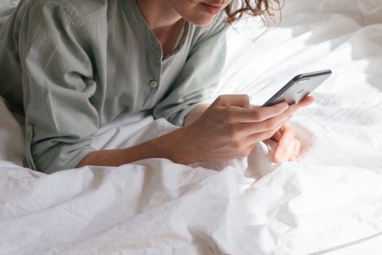 Woman on a bed browsing a phone
