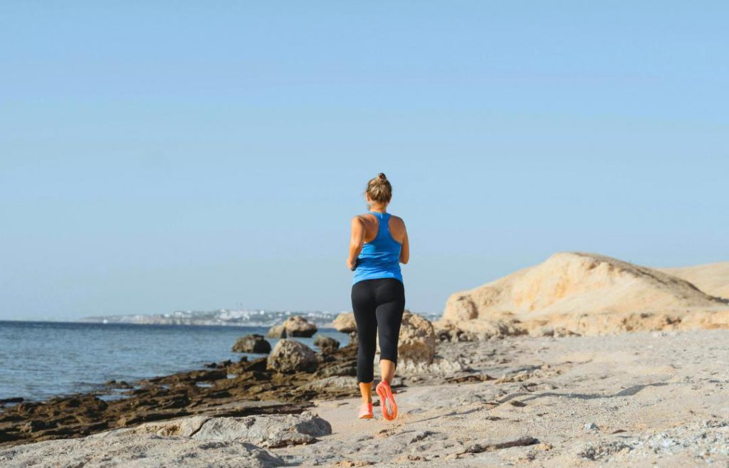 Woman with breast cancer exercising - running on the beach